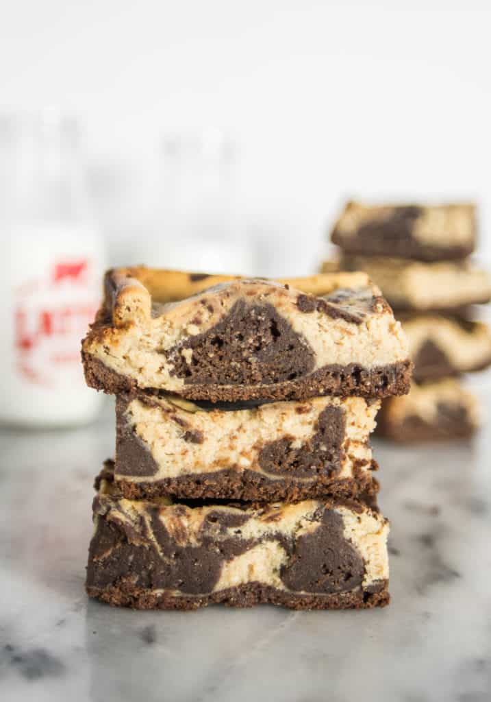 stack of espresso cheesecake brownies with a bottle of milk and more brownies in the background