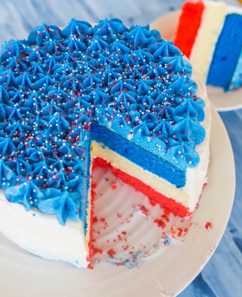 Fourth of July Cheesecake cake with a slice taken out of it to show the red, white, and blue cake layers