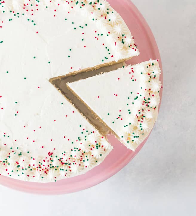 overhead photo of white chocolate eggnog cheesecake layer cake decorated with red and green sprinkles