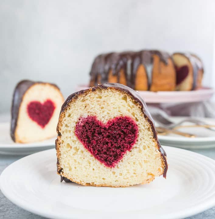 slice of hidden heart bundt cake on a plate with the rest of the cake in the background.