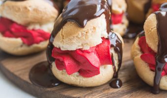 close-up photo of red velvet profiteroles with chocolate glaze dripping down