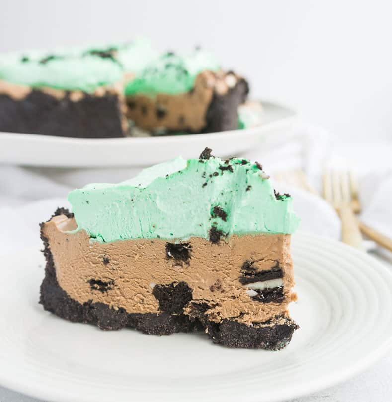 slice of no-bake mint mocha cheesecake on a plate with the cake behind it in the background