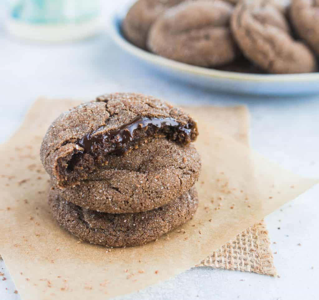 stack of three molten lava cake cookies with the top cookie broken in half to reveal the molten chocolate filling