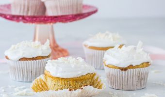 gluten-free coconut cupcakes with coconut sprinkled around them