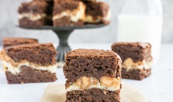 photo of a brownie sitting on a piece of parchment with more peanut butter cream cheese brownies in the background