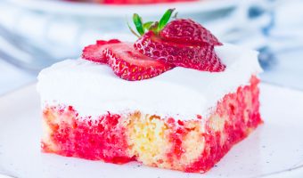 slice of easy strawberry lemonade cake sitting on a plate with another slice in the background