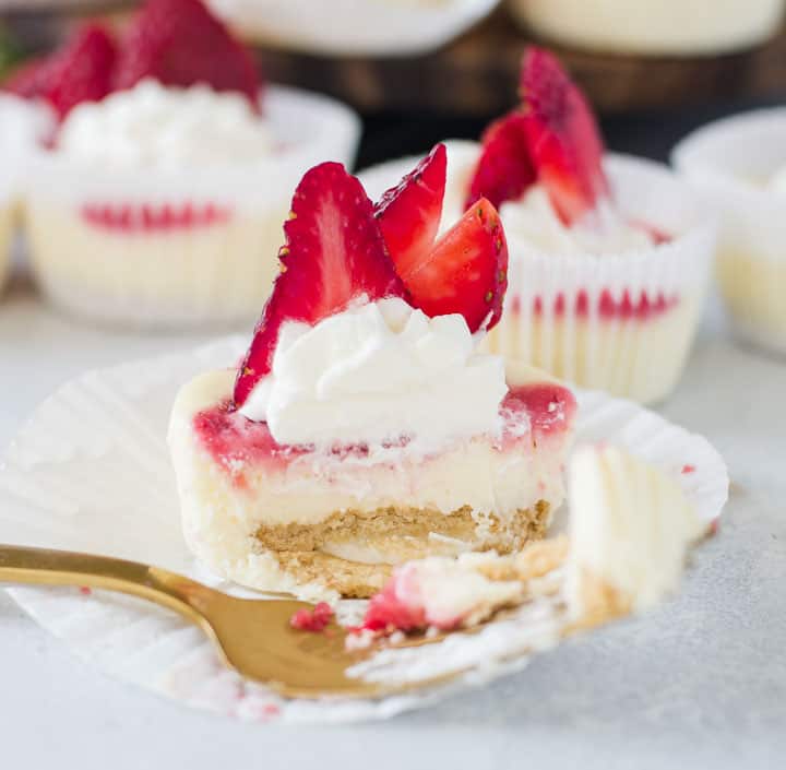 one of the strawberry cheesecake cupcakes with a fork taking a bite out of it