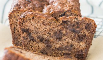loaf of sliced paleo chocolate chip banana bread sitting on a piece of parchment paper