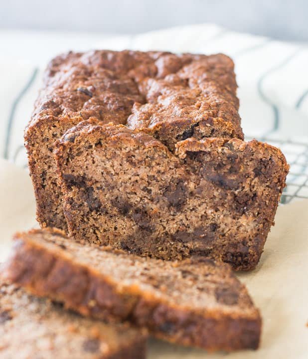 loaf of sliced paleo chocolate chip banana bread sitting on a piece of parchment paper