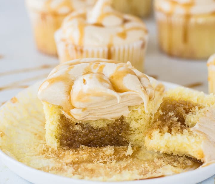 cupcake on a plate split open to show the filling with more caramel cupcakes in the background