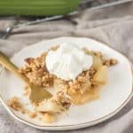 pear crisp on a plate and topped with whipped cream