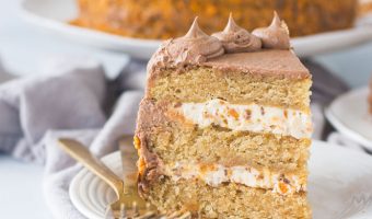 slice of butterfinger cake on a plate next to two forks with the rest of the cake in the background