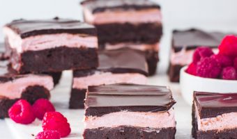 raspberry brownies on a piece of parchment paper with more brownies in the background