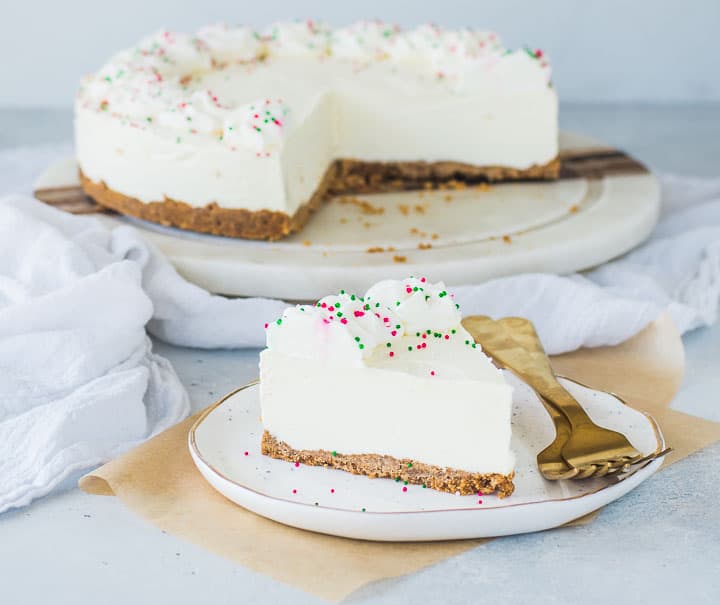 slice of eggnog cheesecake on a plate with the rest of the cake in the background