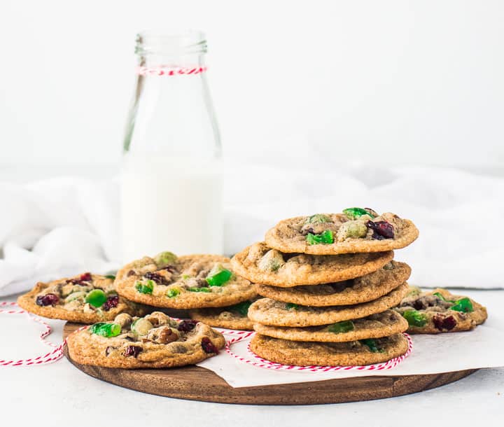 stack of fruitcake cookies on a cutting board with a bottle of milk in the background