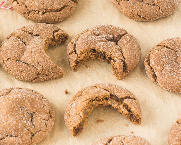 molasses ginger cookies on a piece of parchment with bites taken out of them
