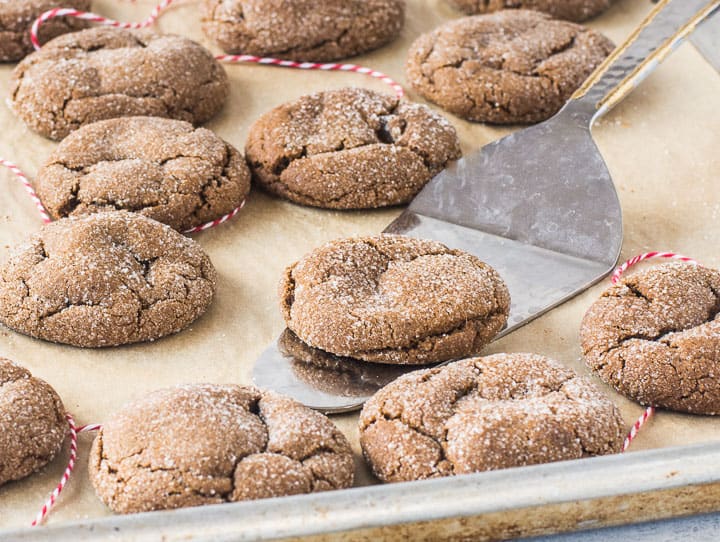 molasses ginger cookies on a baking sheet with a spatula under one of them