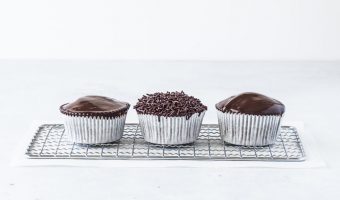 three chocolate ganache cupcakes on a wire rack