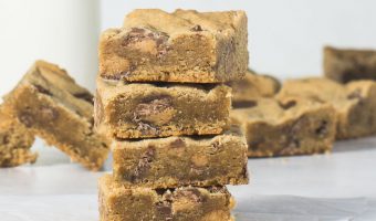 stack of peanut butter cookie bars in front of a bottle of milk