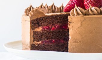 chocolate strawberry cake on a cake stand with a slice taken out of it