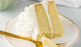 slice of white chocolate cake on a plate with a fork taking a bite out of it