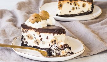 slice of cookie dough cheesecake on a plate with a fork taking a bite out of it and another slice behind it