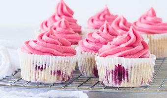 frosted raspberry cupcakes sitting on a wire rack