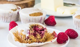 raspberry lemon muffin on a plate with a bite taken out of it and butter in the background