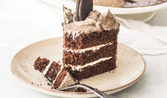slice of Oreo cookie cake on a plate with a fork taking a bite out of it
