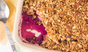 overhead photo of apple blueberry crisp in a pan with a scoop taken out