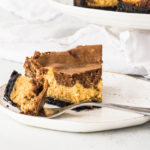 slice of chocolate pumpkin cheesecake on a plate with a fork taking a bite out of it