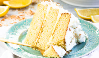 slice of lemon coconut cake on a plate with a fork taking a bite out of it
