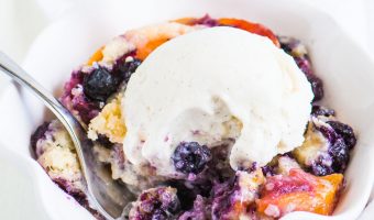 cobbler in a bowl with a scoop of ice cream on top and a fork taking a bite