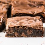 close up photo of sliced brownie with other brownies behind it