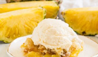 cobbler on a plate with vanilla ice cream on top and fresh pineapple behind it