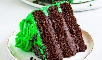 slice of peppermint chocolate cake on a plate in front of the rest of the cake