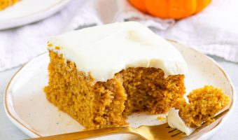 slice of cake on a plate with a fork and a small pumpkin and another slice of cake in the background