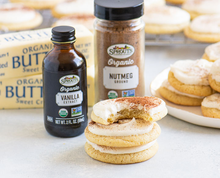 stack of eggnog cookies with butter and jars of vanilla and cinnamon in the background