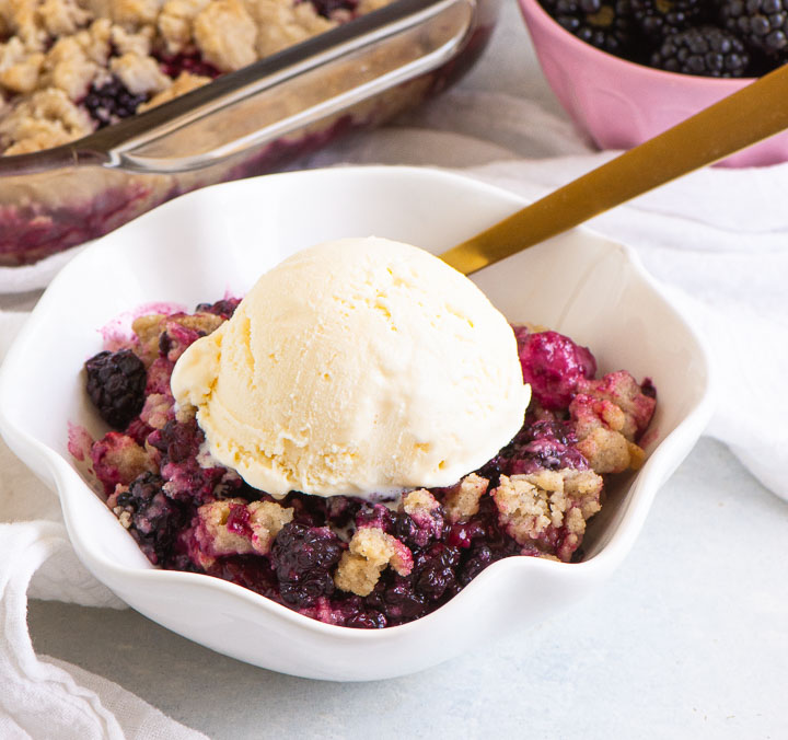 bowl of crumble with a fork and a scoop of ice cream on top