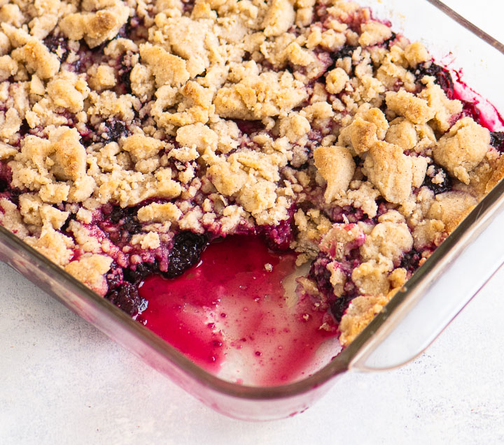 blackberry crumble in a baking dish with a serving scooped out