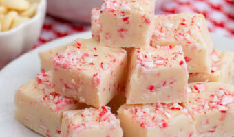 Stack of peppermint candy cane fudge squares on a white plate.