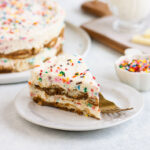 slice of tiramisu on a plate in front of a cake plate with the rest of the tiramisu