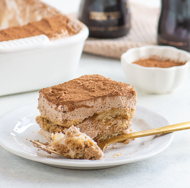 Slice of beeramisu showing layered ladyfingers and mascarpone cream with a forkful taken from the front.
