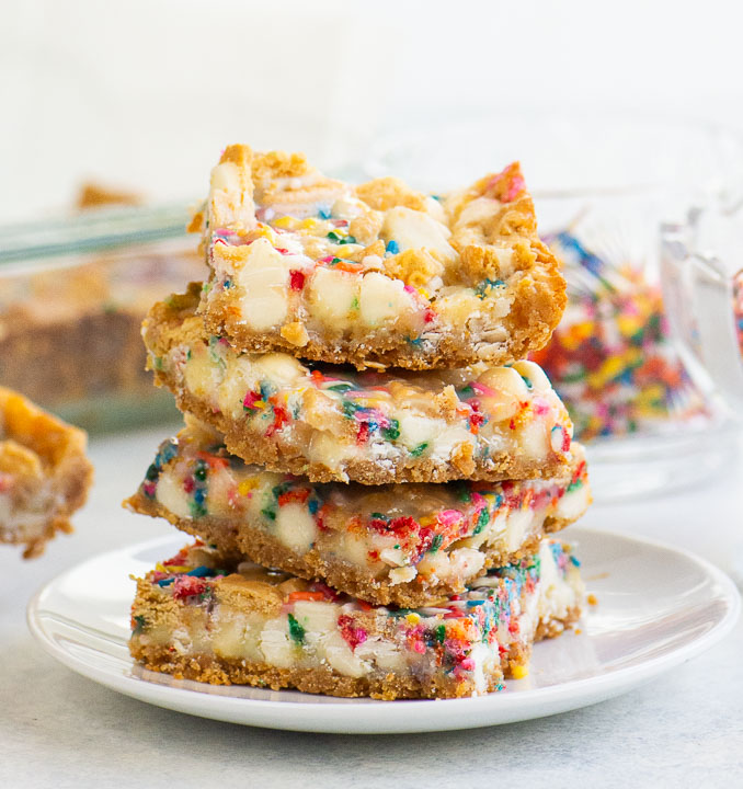 Stack of birthday cake bars with white chocolate, Golden Oreos, and rainbow sprinkles on a white plate.